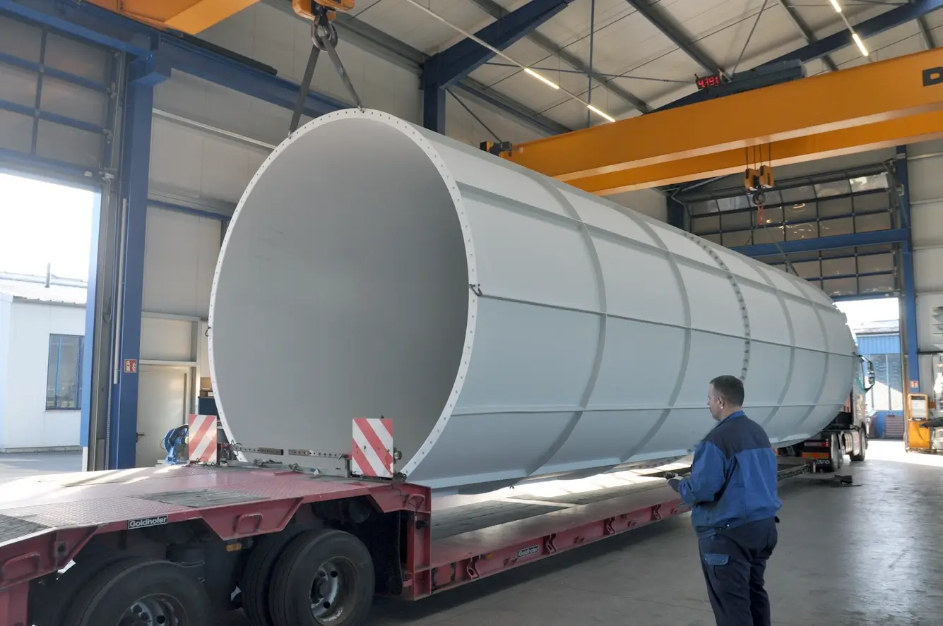 Verladung eines großen Metallsilos in der Fertigungshalle